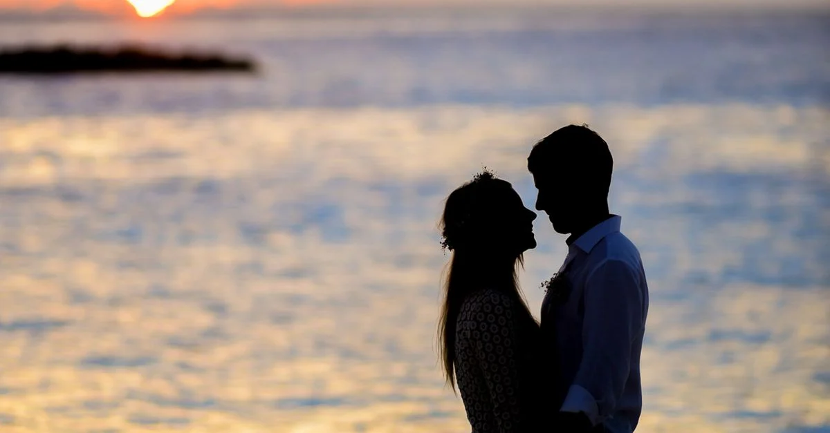 Silhouette of a couple beside the sea at sunset